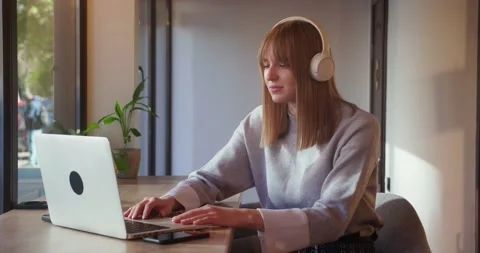 Young attractive female student using laptop for video chat sitting in cafe Stock Footage 169352198