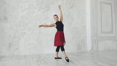 Young attractive girl is dancing on a light background in the studio. slow Stock Footage 94341453