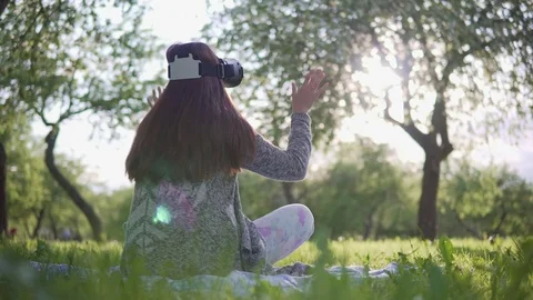Young attractive girl uses virtual reality glasses in the park Stock Footage