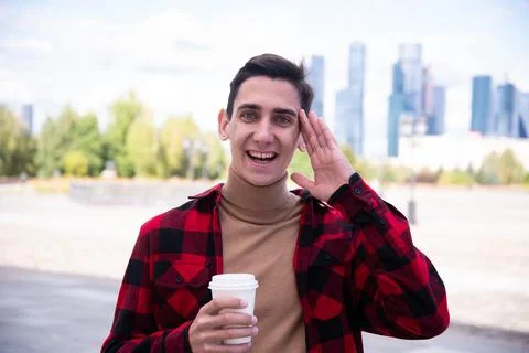 Young attractive guy drinks coffee in the autumn park. Stock Photos