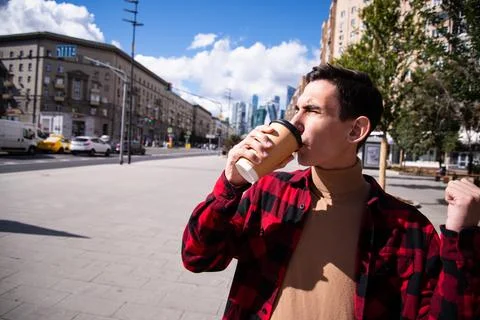 Young attractive guy drinks coffee in the autumn park. Stock Photos