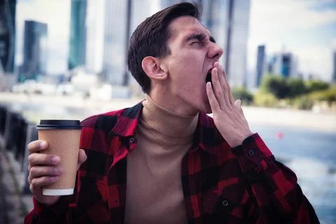 Young attractive guy drinks coffee in the autumn park. Stock Photos