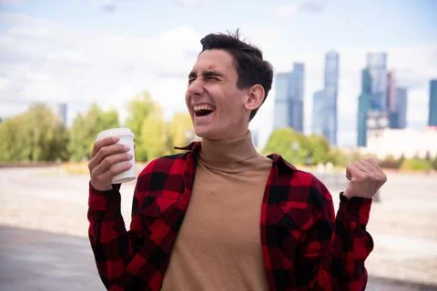 Young attractive guy drinks coffee in the autumn park. Stock Photos