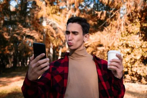 Young attractive guy drinks coffee in the autumn park. Foto stock