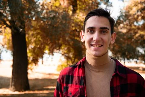 Young attractive guy drinks coffee in the autumn park. Stock Photos