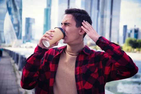 Young attractive guy drinks coffee in the autumn park. Stock Photos