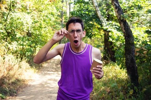 Young attractive guy drinks coffee in the autumn park. Stock Photos