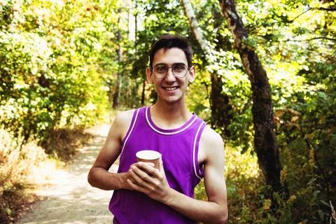 Young attractive guy drinks coffee in the autumn park. Stock Photos
