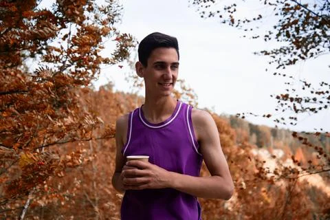 Young attractive guy drinks coffee in the autumn park. Foto stock