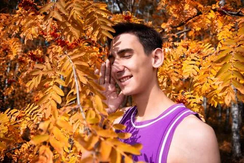 Young attractive guy drinks coffee in the autumn park. Stock Photos