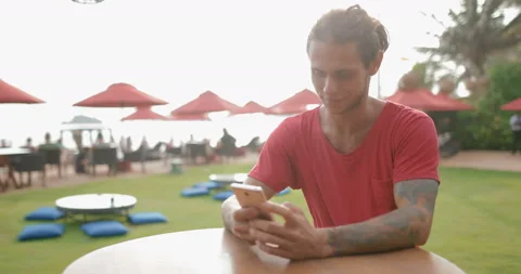 Young attractive guy in a red t-shirt uses a smartphone Stock Footage 107453881