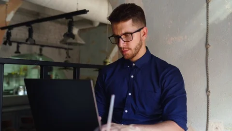 Young attractive hipster freelancer working remotely on laptop in loft cafe Video stock 122766587