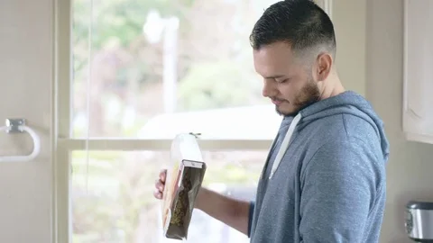 Young attractive hispanic man pours cereal into white bowl Stock Footage 84455381