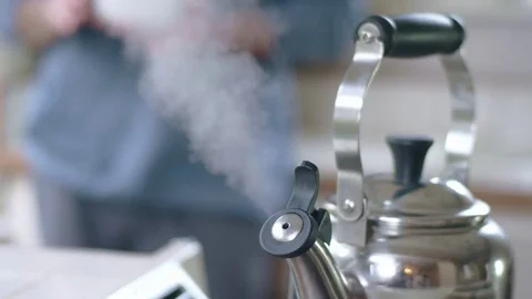 Young attractive hispanic man sets down bowl and pours hot water from tea kettle Stock Footage 84476172