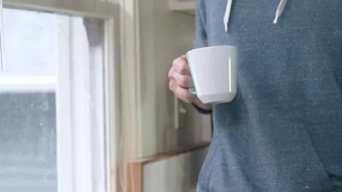 Young attractive hispanic man smells morning cup of tea by bright kitchen window Stock Footage 84478370
