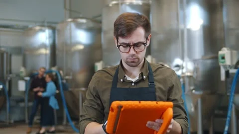 Young attractive male worker using digital tablet and standing near large metal Stock Footage 144535075
