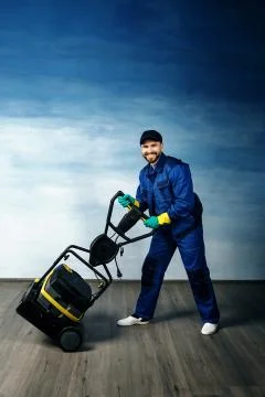 A young attractive man with a beard in a working uniform is standing next to Stock Photos
