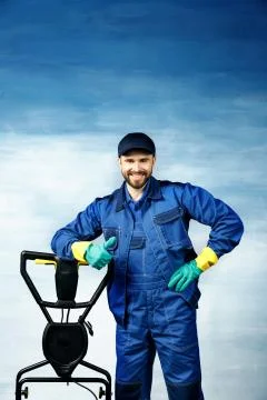 A young attractive man with a beard in a working uniform is standing next to Stock Photos