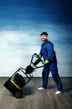 A young attractive man with a beard in a working uniform is standing next to  Stock Photos