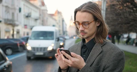 Young attractive man with beard writes message on smartphone. The man has a very Stock Footage 127397604