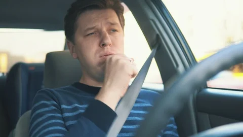 A young attractive man is coughing while driving in car Stock Footage 87348716