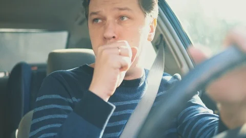 A young attractive man is coughing while driving in car Video stock 87351157