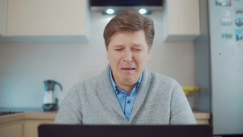Young attractive man crying while sitting at laptop Stock Footage 148348649