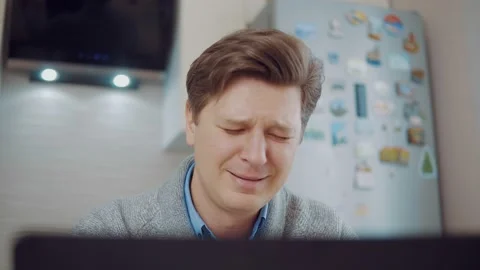 Young attractive man crying while sitting at laptop Stock Footage 148809100