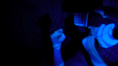 Young attractive man does martial poses in VR-helmet in the spotlight Stock Footage 86824328