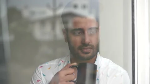 Young attractive man freelancer drinking coffee while looking out of the window Stock-Footage 148254002