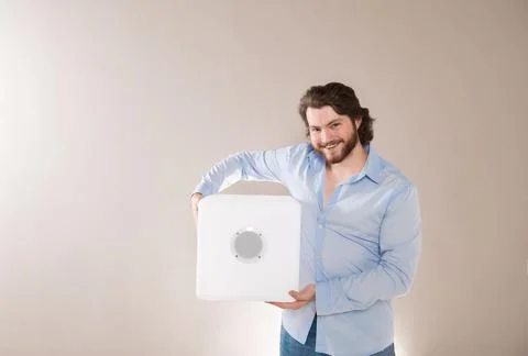 Young attractive man  holding white portable bluetooth speaker on gray backgr Stock Photos