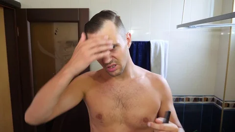 Young attractive man inspects a receding hairline in the bathroom. Baldness. 4k Stock Footage