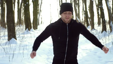 Young attractive man jogger warming up before running outdoors in winter park Stock Footage 87920185