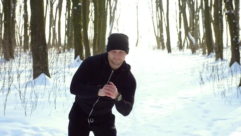 Young attractive man jogger warming up before running outdoors in winter park Stock Footage 87920213