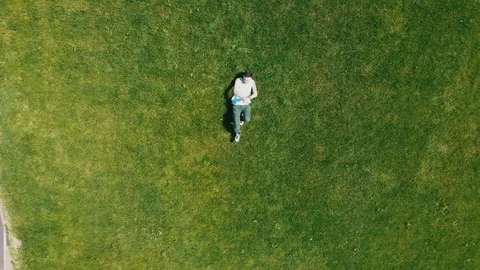 A young attractive man lying on the bright green grass and dancing Stock Footage 112580059