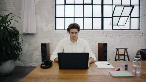 Young attractive man opens his laptop and starts working from home Stock Footage 145734372
