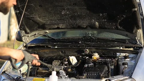 Young attractive man perfusing with water his silver car Stock Footage 90095589