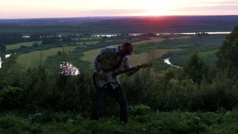 Young attractive man playing guitar at sunset Stock Footage 71369992