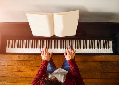 Young attractive man playing piano reading a score at the sunlight Stock Photos