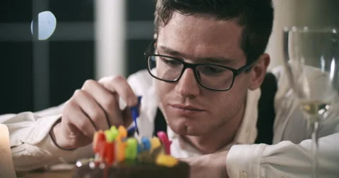 Young attractive man sits alone at the table and sadly eats chocolate from a Видео 172582634