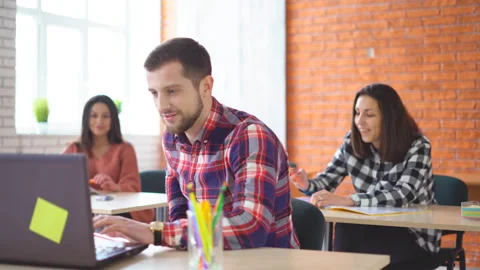 Young attractive man sits in front of a computer and communicates with Vídeos de archivo 86607167