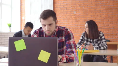 Young attractive man sitting in front of computer and typing on laptop. The Stock Footage 86603493