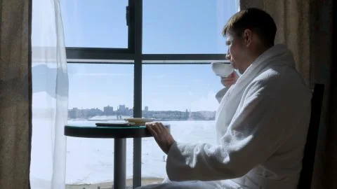 A young, attractive man sitting at a table by the window drinking tea, coffee Foto stock