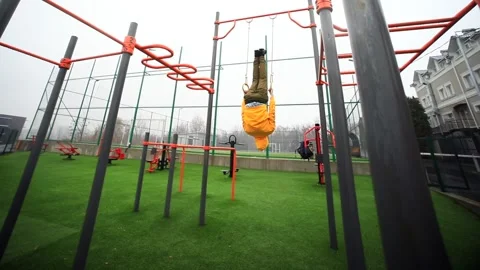 Young attractive man training outside on gymnastic gym rings enjoying healthy li Vidéo 166087530