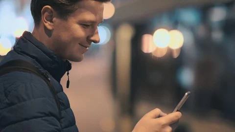 A young attractive man uses a mobile phone in a night city. Stock Footage 88168361