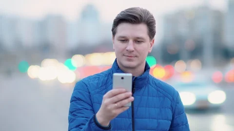 A young attractive man uses a mobile phone in a night city. Stock Footage 88170411