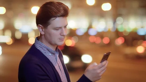 A young attractive man uses a mobile phone in a night city. Stock Footage 89181827
