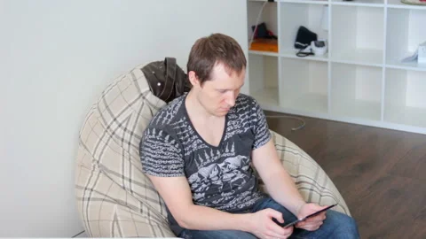 Young attractive man uses tablet sitting in the house Stock Footage 91361740