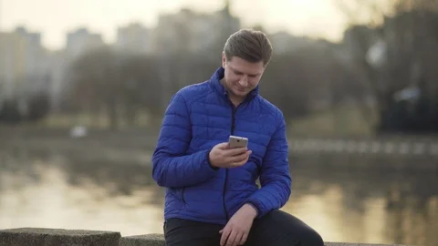 A young attractive man is using a mobile phone at sunset. Stock Footage 88168904