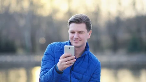 A young attractive man is using a mobile phone at sunset. Video stock 88169023